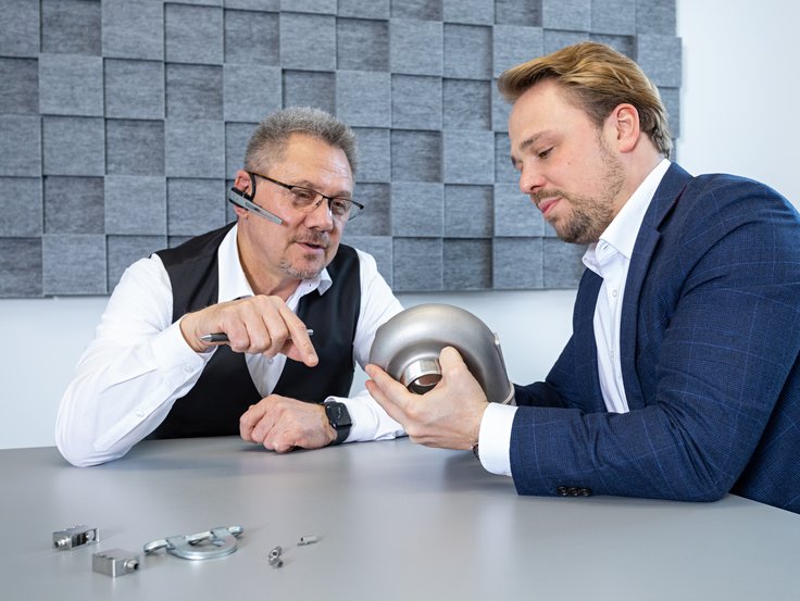 Die Geschäftsführung analysiert ein Muster-Teil der Produktion.