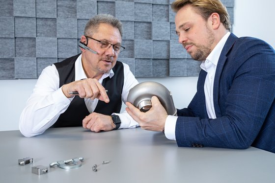 Die Geschäftsführung analysiert ein Muster-Teil der Produktion.