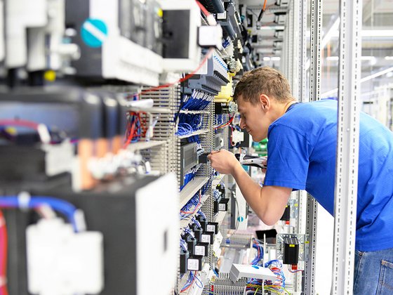 Elektrotechniker, der Installationen an einem Schaltschrank vornimmt. 