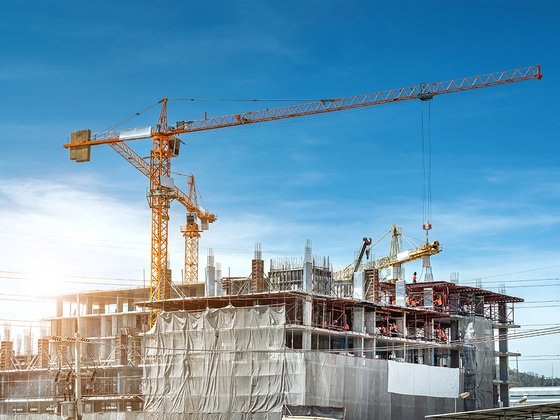 Großbaustelle eines Rohbaus mit Kran und BauarbeiterInnen.