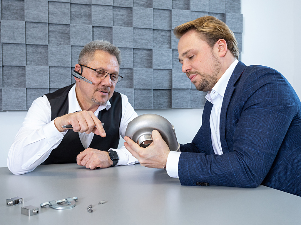 Die Geschäftsführung analysiert ein Muster-Teil der Produktion.